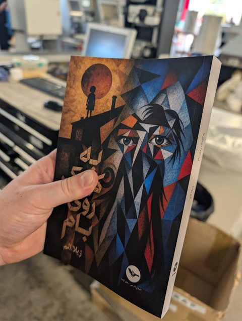 A finished paperback held in the hand on the bindery floor