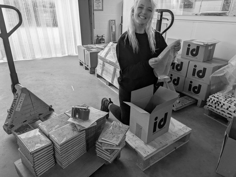 Packing finished books into cartons on a pallet beside the pallet truck, black and white