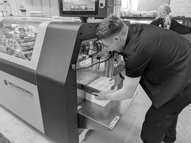 An operator bending to the feed of the thread-sewing machine, black and white