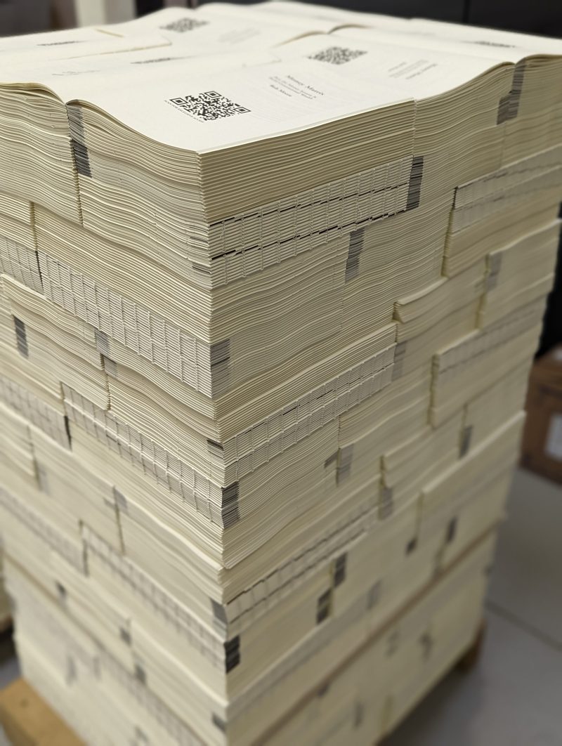 Thread-sewn book blocks stacked high on a pallet in the bindery