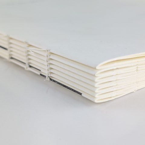 Thread-sewn book block before casing in, linen thread visible through every folded signature