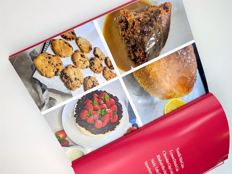 A cookbook open flat to a spread of full-colour food photography, sewn and cased at our Exeter bindery