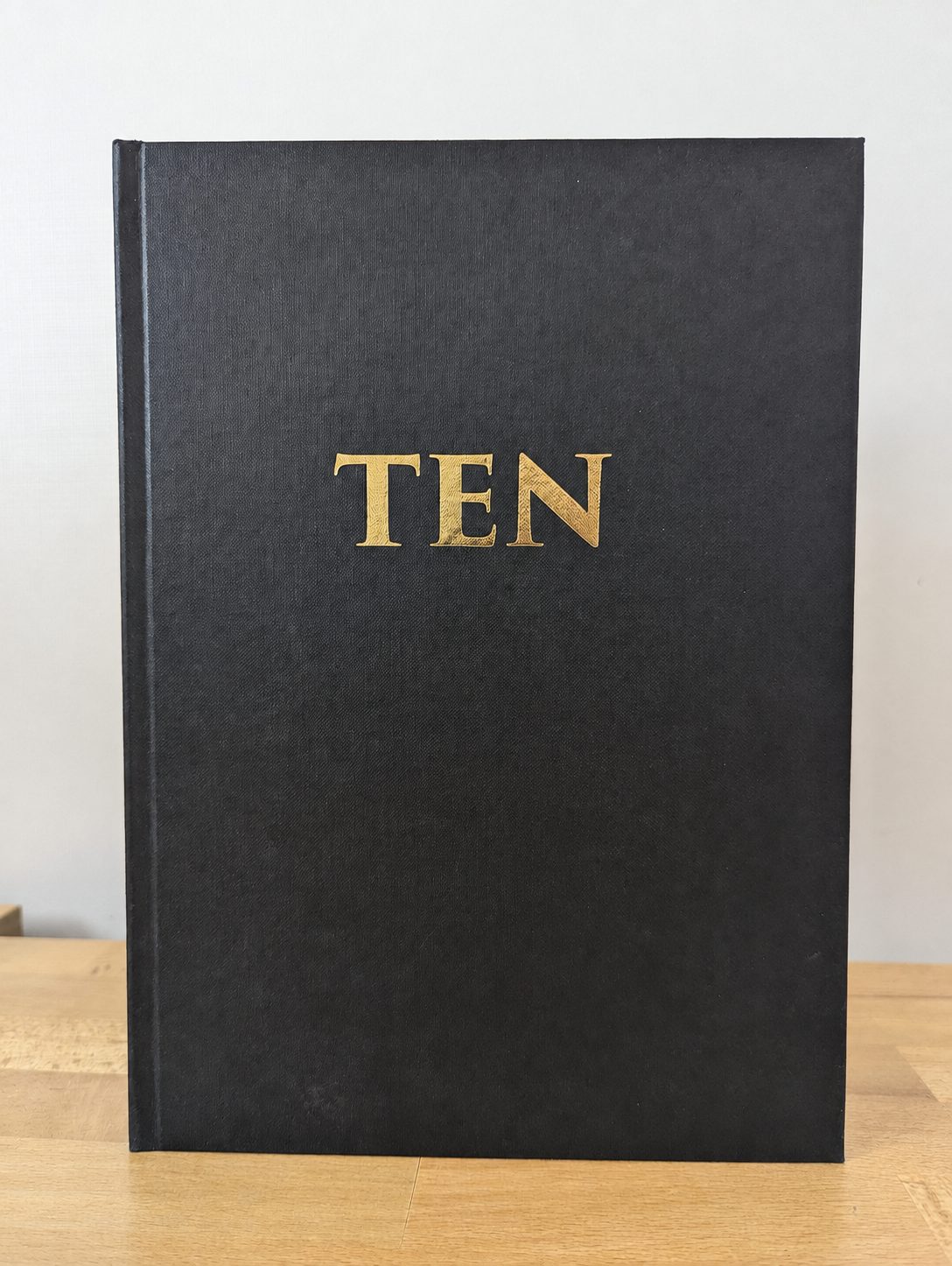TEN, a black cloth hardback with gold foil lettering